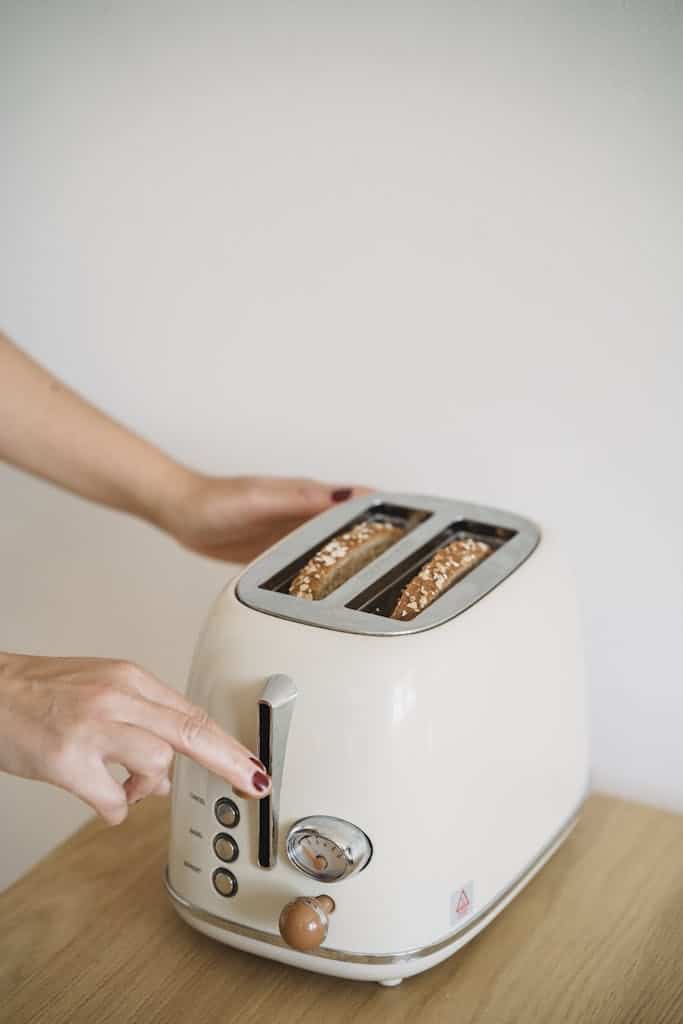 Close-Up Shot of a Person Using a Pop-Up Toaster